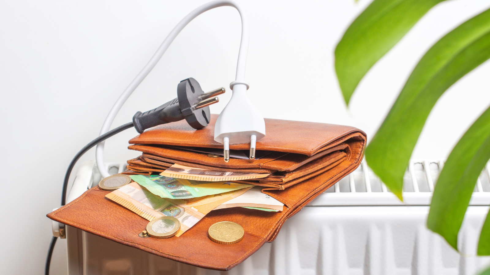 Map met geld die op een radiator ligt met twee stekkers