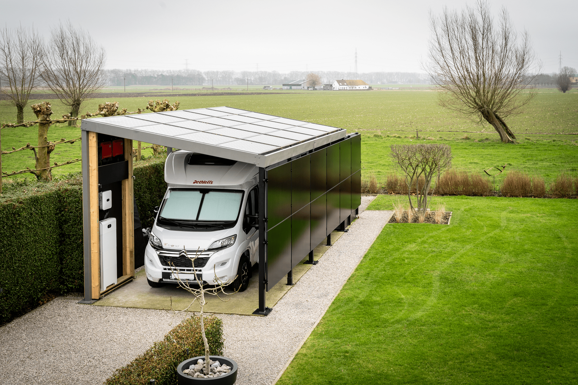 Tuin met een carport voor een camper met zonnepanelen op het dak